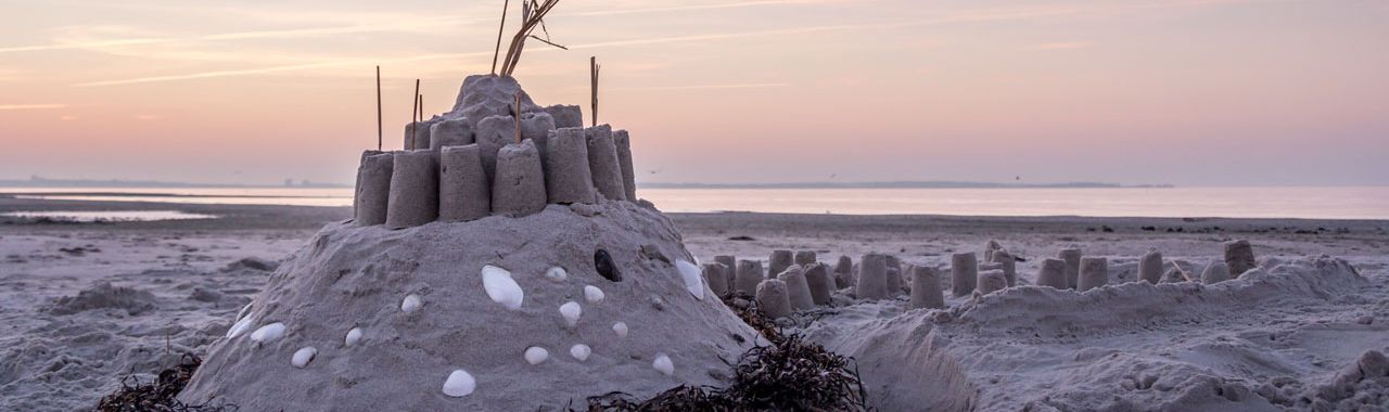 Abbildung einer Sandburg am Strand in der Abenddämmerung